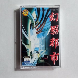 May include: A cassette tape case with a colorful illustration of a futuristic city. The text "ILLUSION CITY" and "幻影都市" are printed on the case. The case is made of clear plastic and has a red sticker with the text "MIDI 対応!" on it.