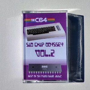 May include: A cassette tape with a purple and white label featuring a keyboard graphic and the text "THE C64". The label also reads "SID CHIP ODYSSEY VOL. 2" and "BEST OF C64 VIDEO GAME MUSIC".
