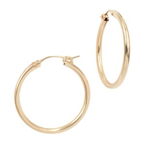 May include: Two gold-colored hoop earrings. The earrings are round and have a simple, classic design. The hoops are made of a shiny, metallic material. The earrings are shown against a white background.