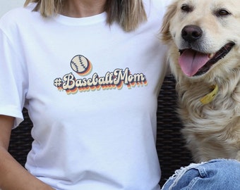 May include: A white t-shirt with a retro-style graphic that says "#Baseball Mom" and a baseball graphic. A golden retriever dog is sitting next to the person wearing the shirt.