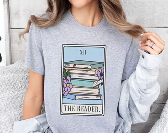 May include: A gray t-shirt with a tarot card design featuring a stack of books and a flower. The card reads "XII THE READER."