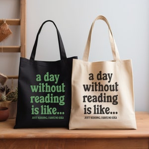 Op de afbeelding: Twee tote bags met de tekst "a day without reading is like... JUST KIDDING, I HAVE NO IDEA" erop gedrukt. E&eacute;n tas is zwart met groene tekst en de andere is beige met zwarte tekst.