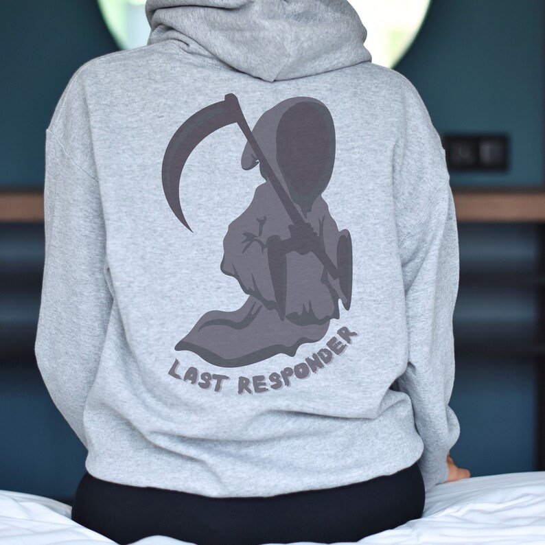 K&ouml;nnte beinhalten: Ein grauer Kapuzenpullover mit einer Grafik einer Kapuzenfigur, die eine Sense h&auml;lt. Der Text "LAST RESPONDER" ist unter der Grafik gedruckt.