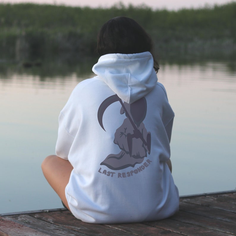 K&ouml;nnte beinhalten: Ein wei&szlig;er Kapuzenpullover mit einem Aufdruck einer Kapuzenfigur, die eine Sense h&auml;lt. Der Aufdruck ist in Graut&ouml;nen gehalten und der Text "LAST RESPONDER" ist unter der Figur gedruckt.