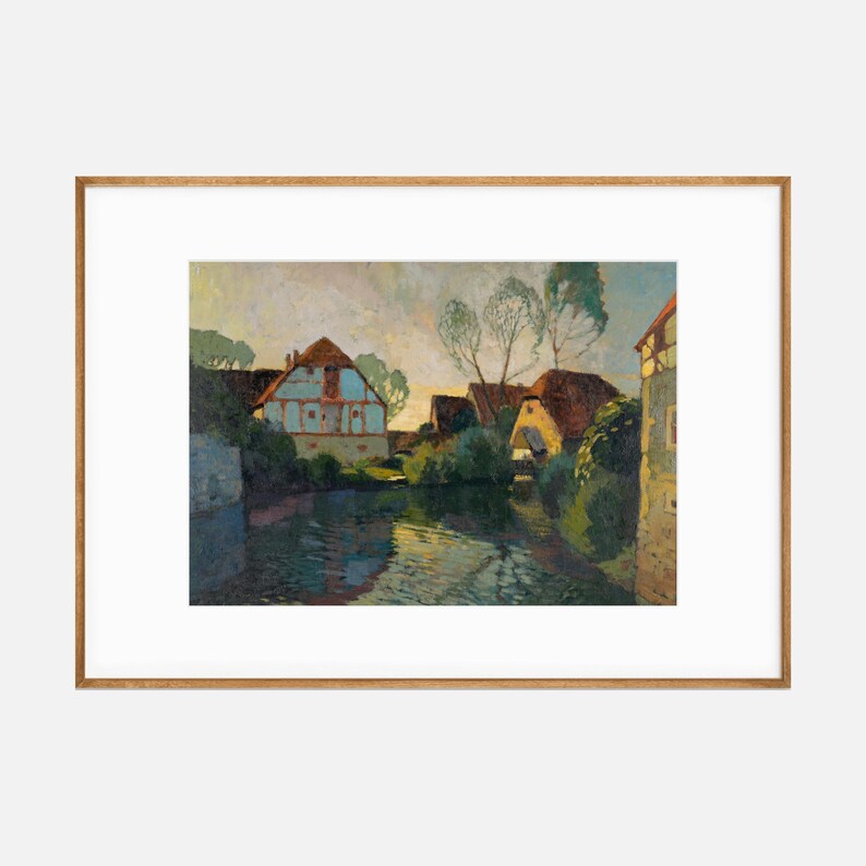 Post-impressionist style painting of a quaint village with colorful houses along a waterway, presented in a light wooden frame with white matting.
