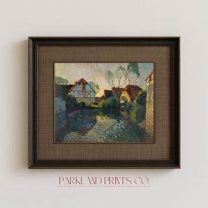 Village landscape artwork mounted in an elegant dark frame with textured brown matting, showing traditional houses nestled along a peaceful waterway.