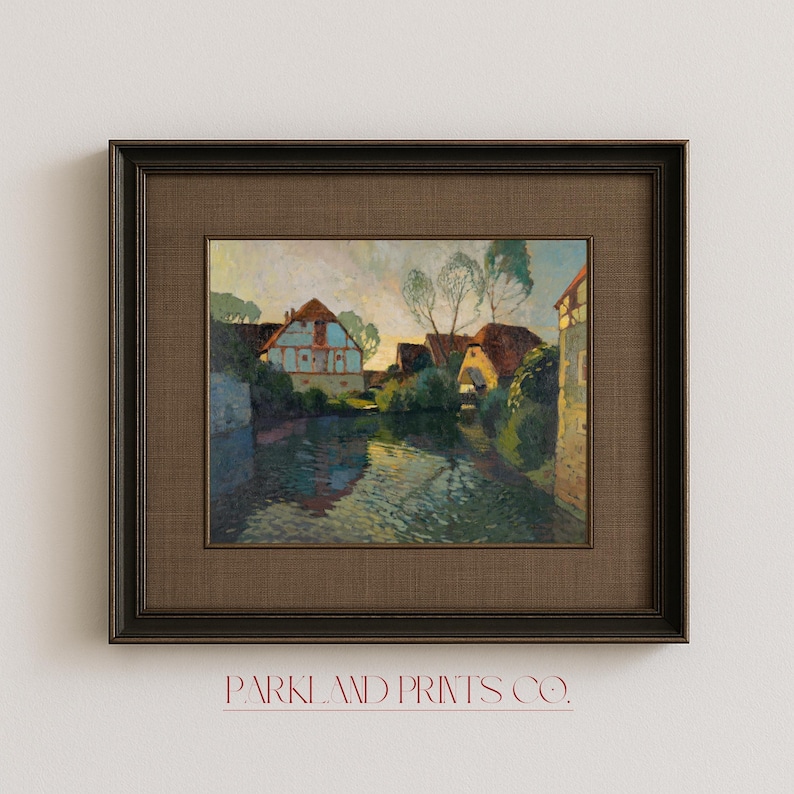 Village landscape artwork mounted in an elegant dark frame with textured brown matting, showing traditional houses nestled along a peaceful waterway.