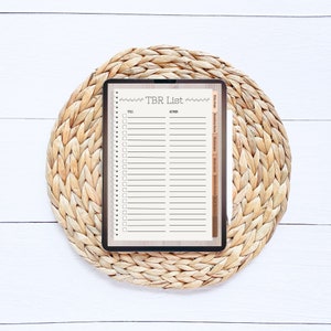 Op de afbeelding: Een digitale tablet met een "TBR-lijst" met een checklist voor boeken om te lezen. De tablet ligt op een geweven strooien onderzetter.