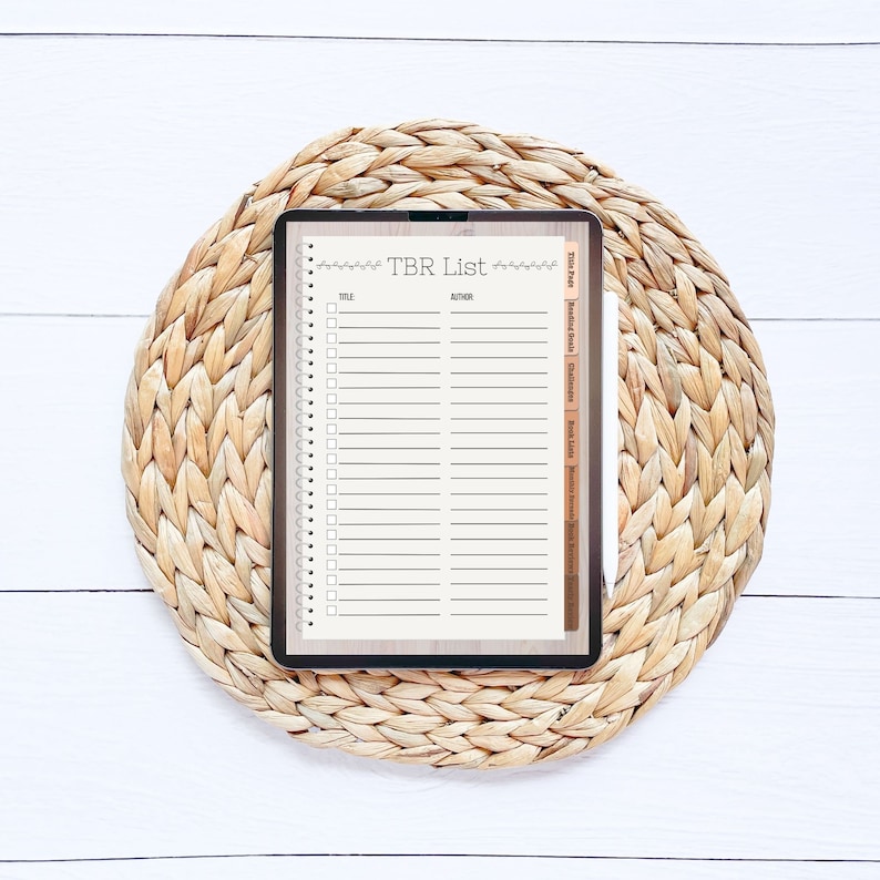 Op de afbeelding: Een digitale tablet met een "TBR-lijst" met een checklist voor boeken om te lezen. De tablet ligt op een geweven strooien onderzetter.
