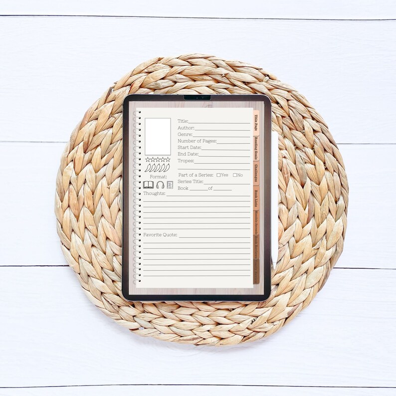 Op de afbeelding: Een digitale boektracker-sjabloon op een tablet met een bruine rieten onderzetter. De sjabloon bevat velden voor titel, auteur, genre, aantal pagina's, startdatum, einddatum, tropes, formaat, deel van een serie, serietitel, boek en gedachten.