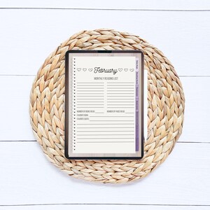 May include: A digital tablet displaying a February reading list template. The template has a light brown background with a white border and includes space to track the number of books and pages read, favorite book, and favorite quote.