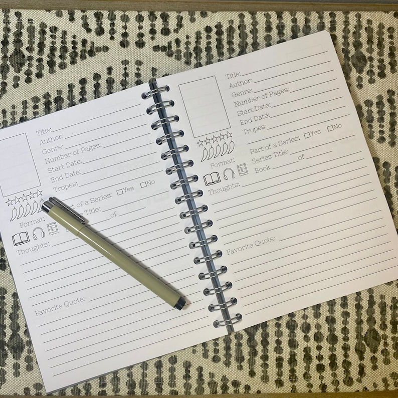 May include: A white book with black lines and text for tracking books read. The book has a spiral binding and is open to a page with the title "Title:" and "Author:".