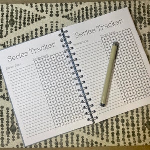 May include: A white spiral bound notebook with a black grid pattern and the text "Series Tracker" and "Series Title: " and "Books Read:" on the cover.