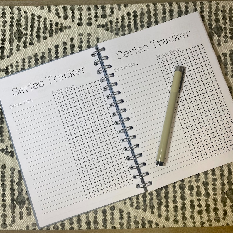 May include: A white spiral bound notebook with a black grid pattern and the text "Series Tracker" and "Series Title: " and "Books Read:" on the cover.