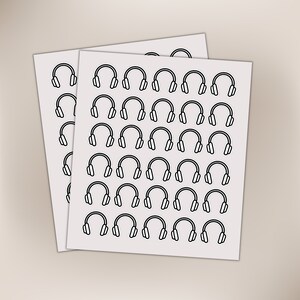 K&ouml;nnte beinhalten: Zwei Stickerb&ouml;gen mit einem sich wiederholenden Muster aus schwarzen Kopfh&ouml;rern. Die Kopfh&ouml;rer sind in einem einfachen, minimalistischen Stil dargestellt, mit einem gebogenen B&uuml;gel und kreisf&ouml;rmigen Ohrmuscheln. Die Aufkleber befinden sich auf hellem Hintergrund.