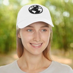 May include: A white baseball cap with a black embroidered globe and airplane design. The globe is surrounded by a stitched circle.