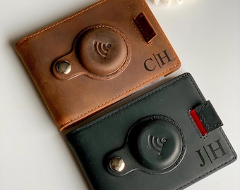 May include: Two leather wallets with a built-in wireless charging pad. The wallet on the left is brown with the initials "C|H" engraved on it. The wallet on the right is black with the initials "J|H" engraved on it.