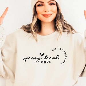 May include: A white sweatshirt with the text "All day every day spring break mode" in a circle with a heart above the word "spring".