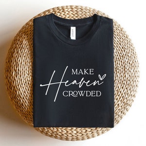 Puede incluir: Camiseta negra con texto blanco que dice "Make Heaven Crowded" con un peque&ntilde;o s&iacute;mbolo de coraz&oacute;n.