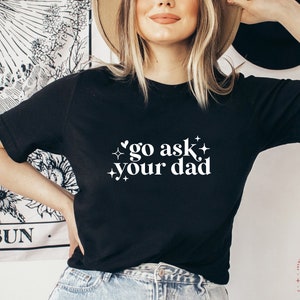 May include: Black t-shirt with white text that reads "go ask your dad" with small stars and a heart graphic.