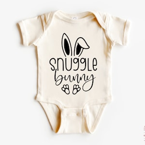 May include: A white baby onesie with black bunny ears and the text "snuggle bunny" with paw prints below.