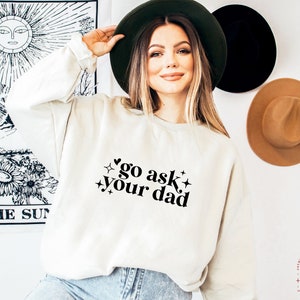 May include: A white sweatshirt with the text "go ask your dad" in black lettering with a heart and stars.