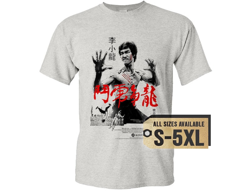 May include: A gray t-shirt with a black and white image of Bruce Lee in a fighting pose. The text "Enter the Dragon" is written in red Chinese characters on the shirt. The text "All Sizes Available S-5XL" is on a gold tag.