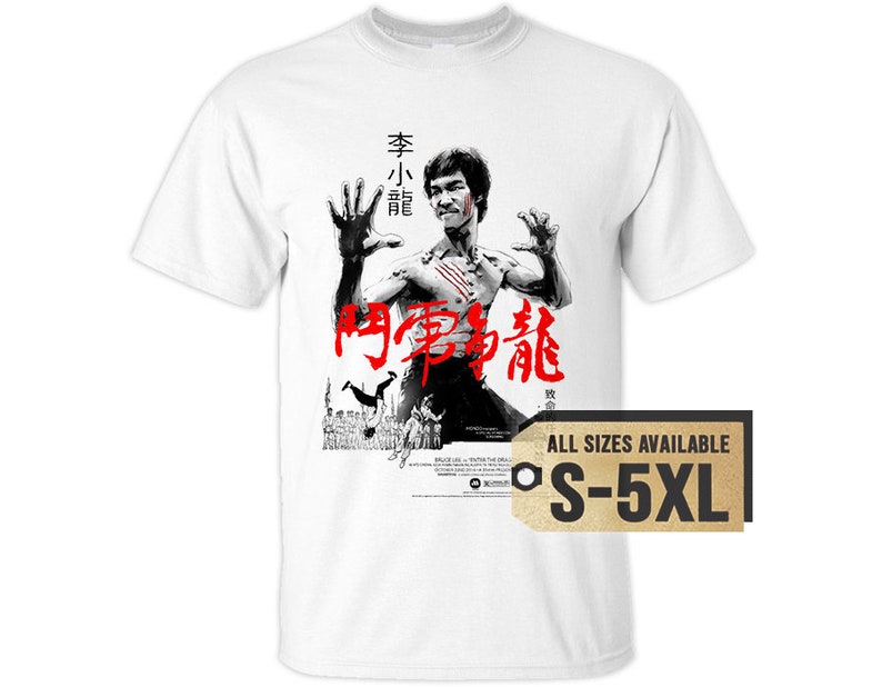 May include: White t-shirt with a black and white image of Bruce Lee in a fighting pose. The text "Enter the Dragon" is written in red Chinese characters on the shirt. The text "All Sizes Available S-5XL" is on a gold tag.
