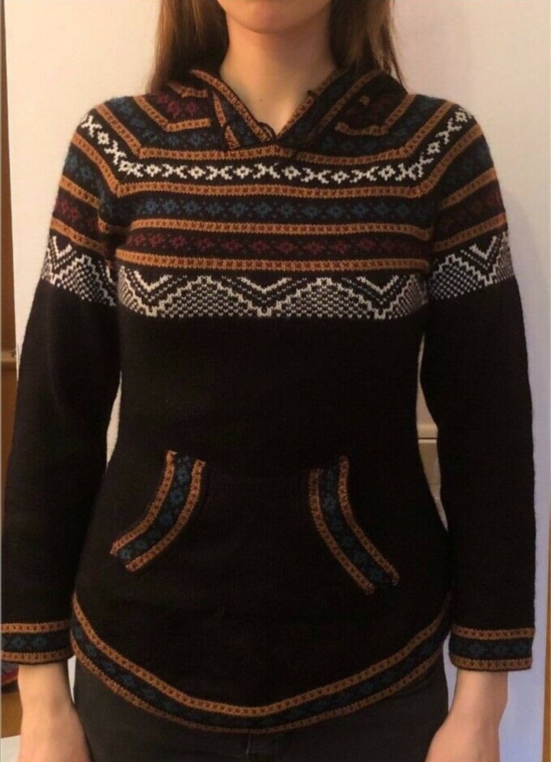 May include: Black hooded sweater with a patterned design in white, brown, and blue. The sweater has a kangaroo pocket and ribbed cuffs. The hood and pocket edges are trimmed with a contrasting pattern.