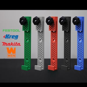 May include: Five different colored wall mounts for power tools. The mounts are made of plastic and have a honeycomb pattern. The colors are green, gray, red, black, and blue.