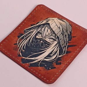 May include: A brown leather coaster featuring a black and white illustration of a person wearing a hooded sweatshirt and a face mask. The illustration has a grunge aesthetic.