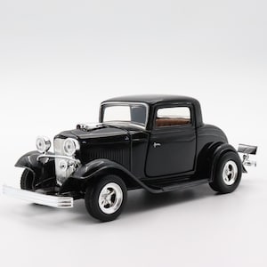 May include: Black 1933 Ford Coupe model car with chrome accents. The car has a black interior and a detailed engine.