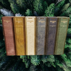 May include: Five wooden boxes with different wood grain patterns and a gold trim. Each box has the word "GROSS" printed on the front in gold lettering. The boxes are arranged in a row from left to right.