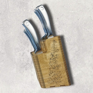 Puede incluir: Un bloque de cuchillos de madera con un diseño floral, que contiene un juego de cuatro cuchillos de plata.