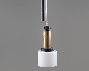 May include: A modern pendant light fixture with a cylindrical design. It features a brass-colored top, a black and brass midsection, and a white, cylindrical bottom. The light hangs from three white cords.