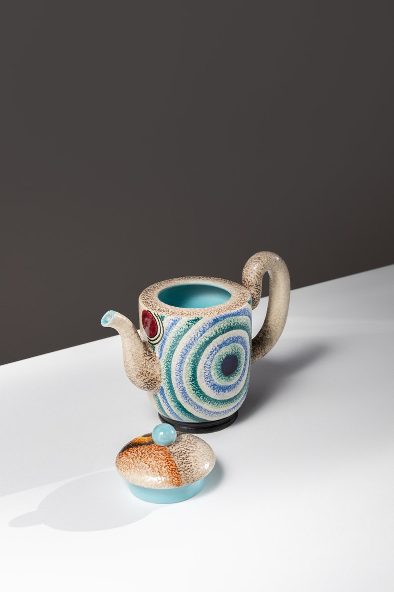 May include: A ceramic teapot with a blue, green, and brown geometric pattern. The teapot has a lid with a similar pattern.