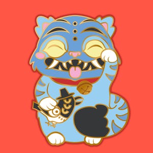 Op de afbeelding: Een blauwe cartoon kat pin met een gouden omtrek, met een bel kraag en het vasthouden van een vis met een hoed. De kat heeft gesloten ogen, een rode tong en een zwart-gouden ontwerp. De achtergrond is rood.