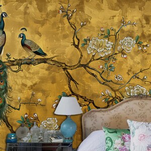 K&ouml;nnte beinhalten: Eine goldfarbene Wandmalerei mit einem gro&szlig;en Pfau und einem kleineren Pfau, der auf einem Ast mit wei&szlig;en Bl&uuml;ten sitzt. Die Wandmalerei befindet sich in einem Schlafzimmer mit einem Bett und einer Lampe.