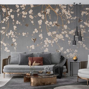 May include: A living room interior design with a gray sofa and two armchairs. The wall features a gray wallpaper with a floral pattern of white blossoms and brown branches. The wallpaper has a subtle textured look.