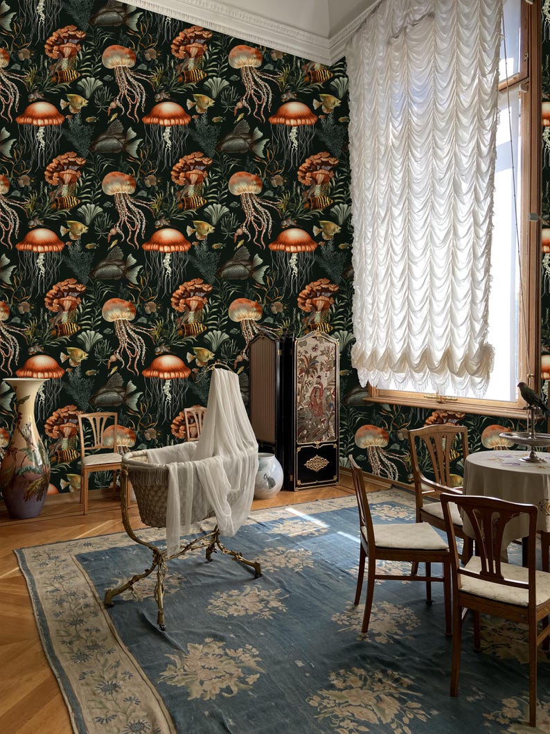 May include: A room with a dark green wallpaper featuring a repeating pattern of jellyfish, fish, and coral. A baby cradle with a white veil sits on a blue floral rug. Wooden chairs and a table are arranged in the room, with a large window and white curtains.