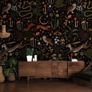 May include: A dark brown wooden console table with a black chair and two potted plants in front of it. The wall behind the furniture is covered in a black wallpaper with a repeating pattern of animals, plants, and mushrooms.