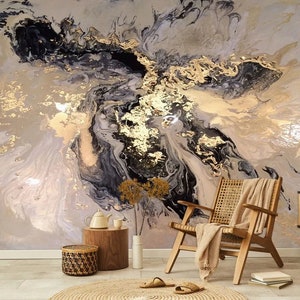 May include: Abstract wall art featuring a swirling pattern of black, gold, and white paint. The art is displayed in a living room setting with a chair, a side table, and a vase of flowers.