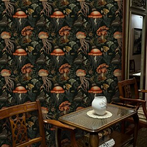 May include: Dark wallpaper featuring a repeating pattern of orange jellyfish, fish, and seaweed on a black background. The room includes wooden furniture, a glass-topped table, and a white vase.
