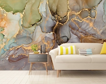 May include: Abstract wall art featuring a swirling pattern of gray, blue, green, and gold paint. The background is a light gray color. The art is displayed on a wall in a living room setting with a couch and a side table.