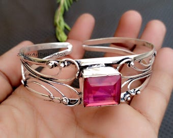 Puede incluir: Una pulsera de plata con un diseño abierto y una gran piedra preciosa rosa cuadrada en el centro. La pulsera tiene intrincados detalles de filigrana y el texto "SilverArtDesign925".