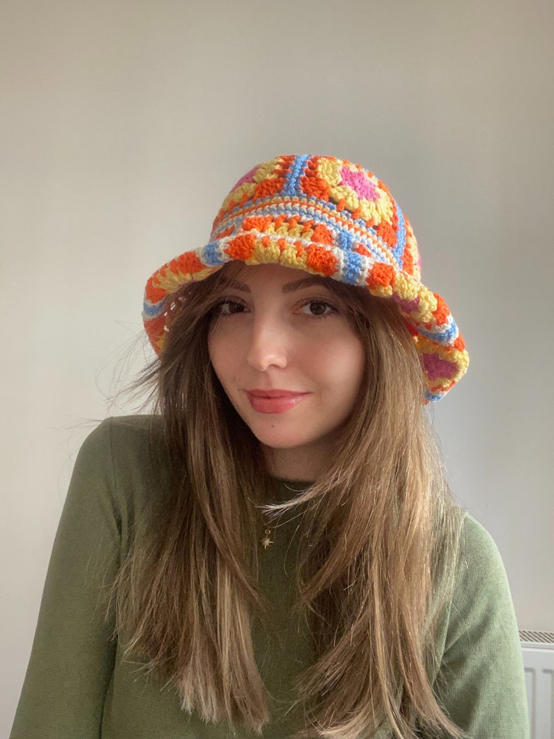 May include: A crocheted bucket hat with a colorful geometric pattern in shades of orange, yellow, pink, and blue.