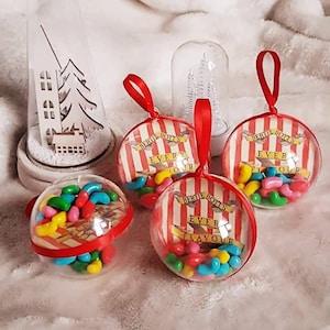 Peut inclure: Quatre boules de Noël transparentes avec du papier rayé rouge et blanc à l'intérieur. Chaque boule contient des bonbons gélifiés colorés et le texte "Bertie Botts Every Flavor Beans".