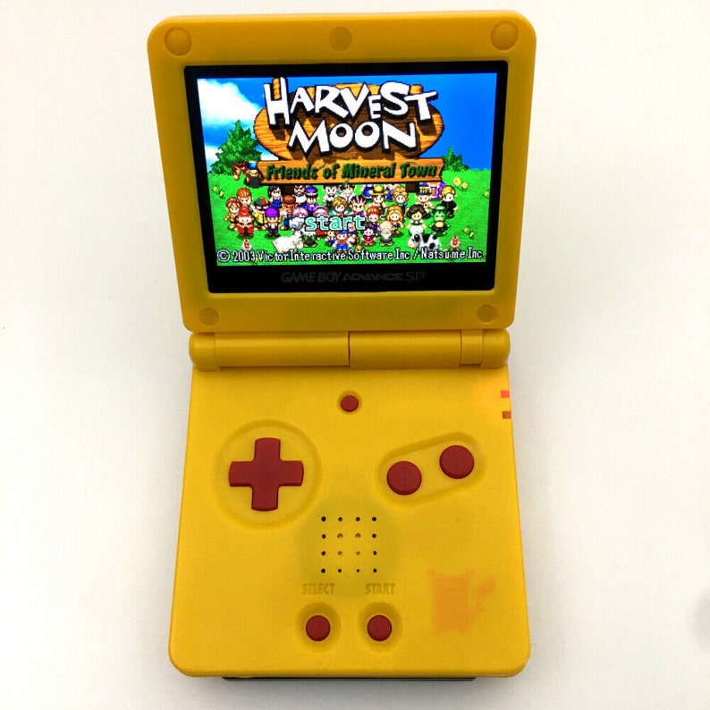Op de afbeelding: Een gele Game Boy Advance SP handheld-spelconsole met een rode en zwarte bedieningsknoppen. Het scherm toont het spel Harvest Moon: Friends of Mineral Town.
