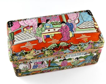 May include: Rectangular, hand-painted decorative box with a detailed scene of figures in traditional attire. The box features a vibrant color palette of red, pink, green, and blue, with floral and geometric patterns. The box is likely made of porcelain.