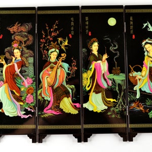 Puede incluir: Una pantalla negra de cuatro paneles con ilustraciones detalladas de mujeres con vestimenta asiática tradicional. Cada panel representa una escena diferente con colores vibrantes, incluyendo rojo, rosa, amarillo y verde. La pantalla tiene un marco y base de madera oscura.